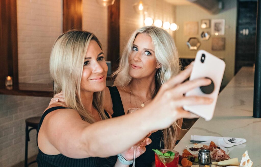blond girl taking selfie with friend